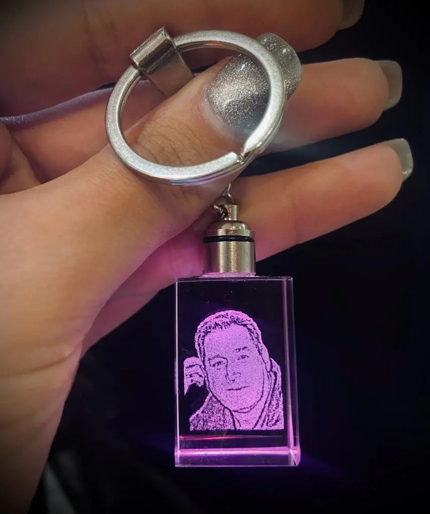 Llavero de cristal 2D con el retrato de una mujer, iluminado en morado y sostenido en la mano